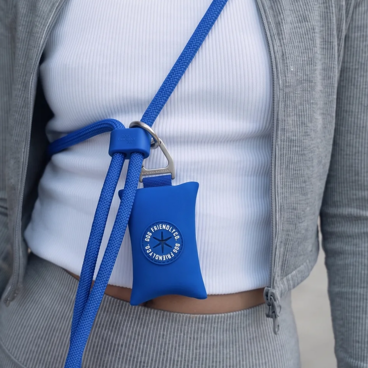 Classic blue poop bag holder attached to a hands-free dog leash worn around the shoulder