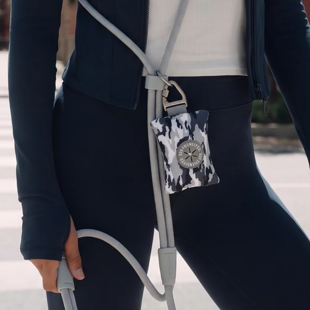 Grey Camo poop bag holder attached to a hands-free dog leash worn around the shoulder